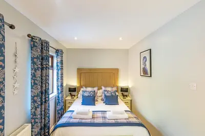 a bedroom with a large bed with blue pillows at Bluebell Lodge 7 with Hot Tub in Newton Stewart