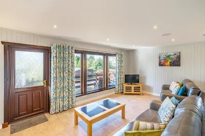 a living room with a couch and a tv at Bluebell Lodge 7 with Hot Tub in Newton Stewart