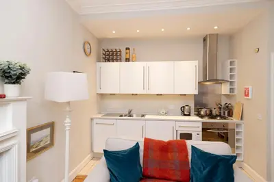 a kitchen with white cabinets and blue pillows at Charming Hideaway in Edinburgh City Centre in Edinburgh