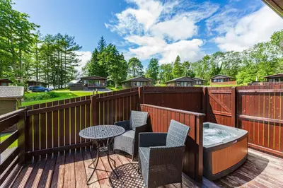 a deck with a table and chairs and a hot tub at Bluebell Lodge 9 with Hot Tub in Newton Stewart