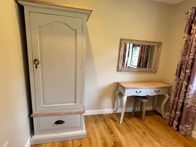 a bedroom with a cabinet and a table and a mirror at Bluebell Lodge 9 with Hot Tub in Newton Stewart