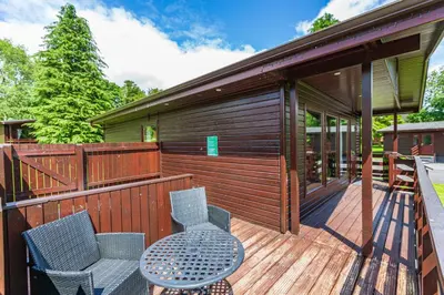 a wooden deck with a table and chairs on it at Bluebell Lodge 9 with Hot Tub in Newton Stewart