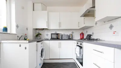 a white kitchen with white cabinets and appliances at Ferguson House in Airdrie