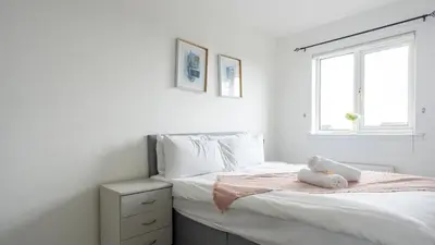 a white bedroom with a bed and a window at Ferguson House in Airdrie
