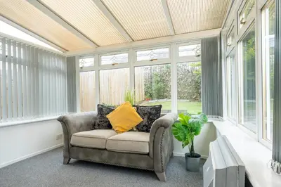 a conservatory with a chair in a room with windows at Ferguson House in Airdrie