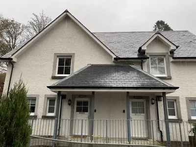a white house with a fence in front of it at Brodie Cottage in Killin