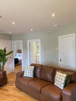 a brown leather couch in a living room with a bedroom at Birch Lodge 18 with Hot Tub in Newton Stewart