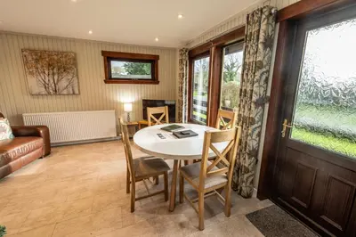 a living room with a table and chairs and a window at Birch Lodge 20 with Hot Tub in Newton Stewart