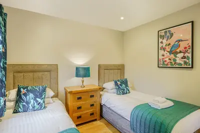 a bedroom with two beds and a lamp on a dresser at Birch Lodge 22 with Hot Tub in Newton Stewart
