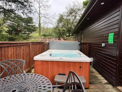 a hot tub on a deck with a table and chairs at Birch Lodge 23 with Hot Tub in Newton Stewart