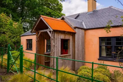 a house with an orange roof and a green fence at The Artist's House at Jupiter Artland in Kirknewton