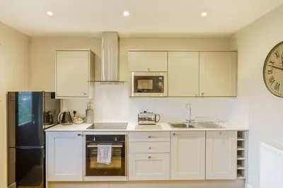 a kitchen with white cabinets and a clock on the wall at Conifer Lodge 25 with Hot Tub in Newton Stewart