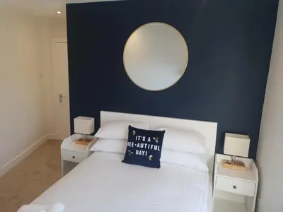 a bedroom with a white bed with a mirror on the wall at The Creek-Stone Den in Oban