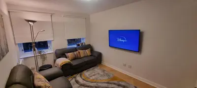 a living room with a couch and a tv on a wall at Merchantcityflat in Glasgow