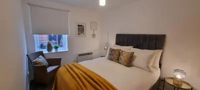 a bedroom with a bed and a chair and a window at Merchantcityflat in Glasgow