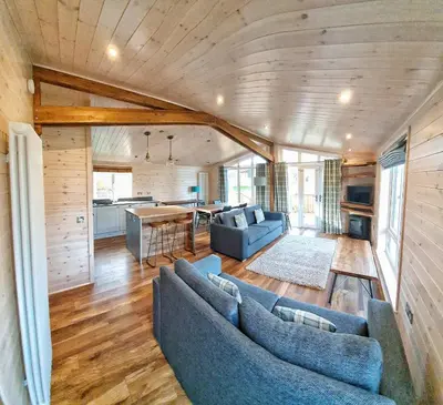 a living room with two blue couches and a kitchen at Skyline Lodge Loch Lomond Castle Lodges in Balloch