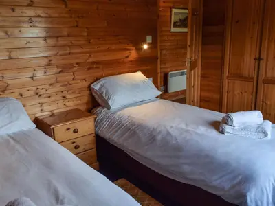 two beds in a room with wooden walls at Catkin Lodge - Uk39646 in Lunga