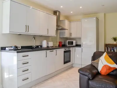 a kitchen with white cabinets and a couch at Birch - Apartment in Aberfoyle