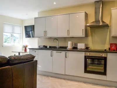 a kitchen with white cabinets and an oven at Birch - Apartment in Aberfoyle