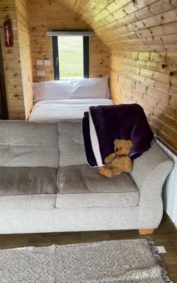 a teddy bear sitting on a couch in a bedroom at Hare's Warren in Bathgate