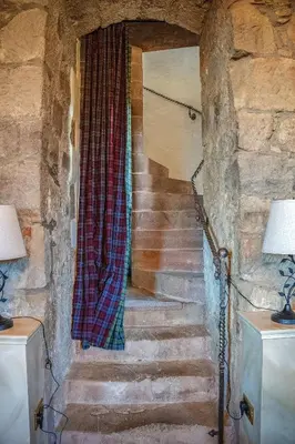 a stairway with a plaid curtain in a stone wall at Craigiehall Temple in Edinburgh