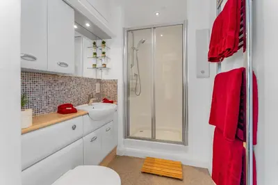 a bathroom with a sink and a shower with red towels at Craigiehall Temple in Edinburgh