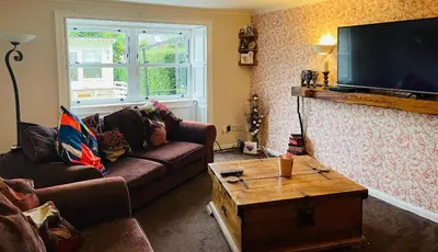 a living room with a couch and a tv at Karibu Cottage near the airport in Edinburgh