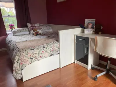 a small bedroom with a bed and a desk at Karibu Cottage near the airport in Edinburgh