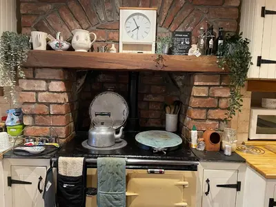 a kitchen with a stove with a stone wall at Karibu Cottage near the airport in Edinburgh