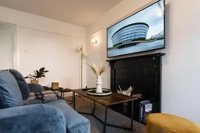 a living room with a couch and a tv on a wall at Finnieston 1-Bed - Walk to Hydro & Bars - Sleeps 2 in Glasgow