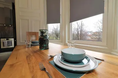 a dining room table with plates and a vase on it at Signature - Linden House Flat 3 in Airdrie