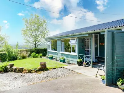 a green house with a garden in front of it at The Old School Bike Shed in Stirling