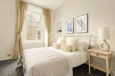 a white bedroom with a bed and a window at The Stockbridge Snug by Calton Living in Edinburgh