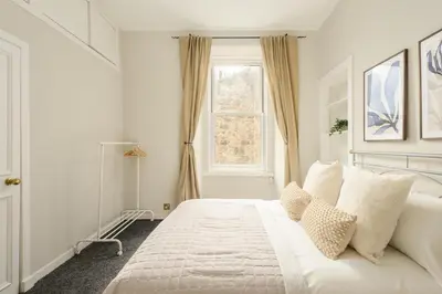 a white bedroom with a large bed and a window at The Stockbridge Snug by Calton Living in Edinburgh