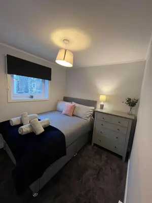 a bedroom with a bed and a dresser and a window at Breadalbane Apartment in Oban