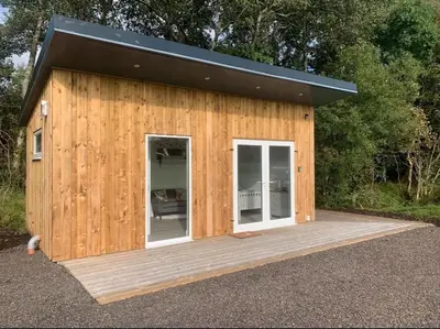 a small wooden building with a black roof at Lora Cabin in Oban