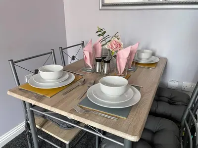 a wooden table with plates and bowls and flowers on it at Spacious one bedroom flat, entire property. in Greenock