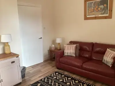a living room with a brown leather couch and a table at Hillview, Ground floor apartment, Largs in Largs