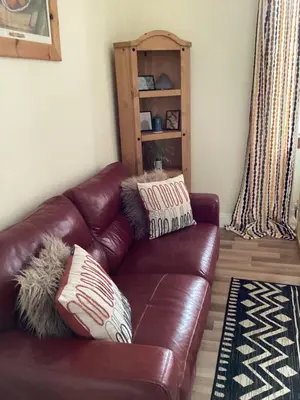 a brown leather couch with pillows in a living room at Hillview, Ground floor apartment, Largs in Largs