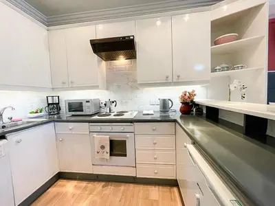 a kitchen with white cabinets and a stove top oven at Snug Studio on The Grassmarket, 5mins from Castle in Edinburgh