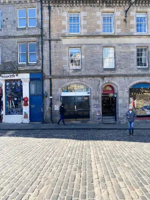 a person walking in front of a brick building at Snug Studio on The Grassmarket, 5mins from Castle in Edinburgh