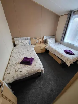 two beds in a room with purple pillows on them at Red Squirrel Lodge in Auchterarder