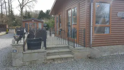 a wooden house with a gate and a fence at Red Squirrel Lodge in Auchterarder