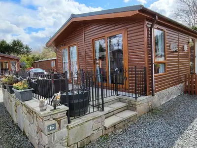 a small cabin with a porch and a fence at Red Squirrel Lodge in Auchterarder