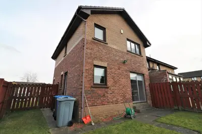 a brick house with a fence and a trash can at Signature - Moore View in Hamilton