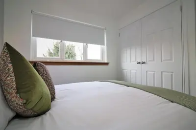 a bedroom with a bed with green pillows and a window at Signature - Moore View in Hamilton