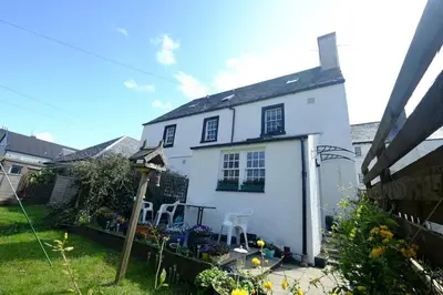 a white house with two chairs in a yard at Cosy cottage flat in Inveraray