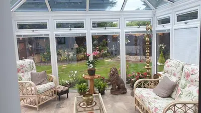 a conservatory with couches and chairs in a room with windows at Ceylon HomeStay in Knightswood
