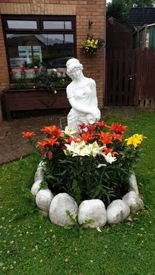 a statue in a garden with flowers and rocks at Ceylon HomeStay in Knightswood