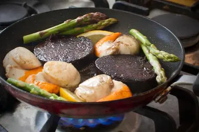 a pan with meat and vegetables on a stove at Loch Gorm House in Bruichladdich